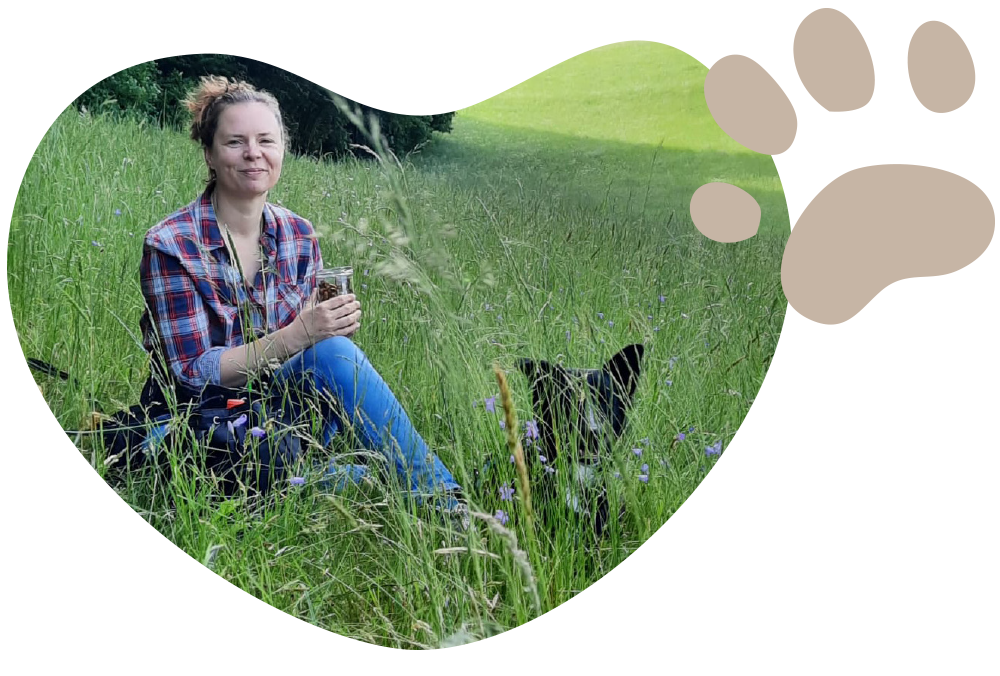 Leontien Vogels sitzt auf einer Wiese mit Hund